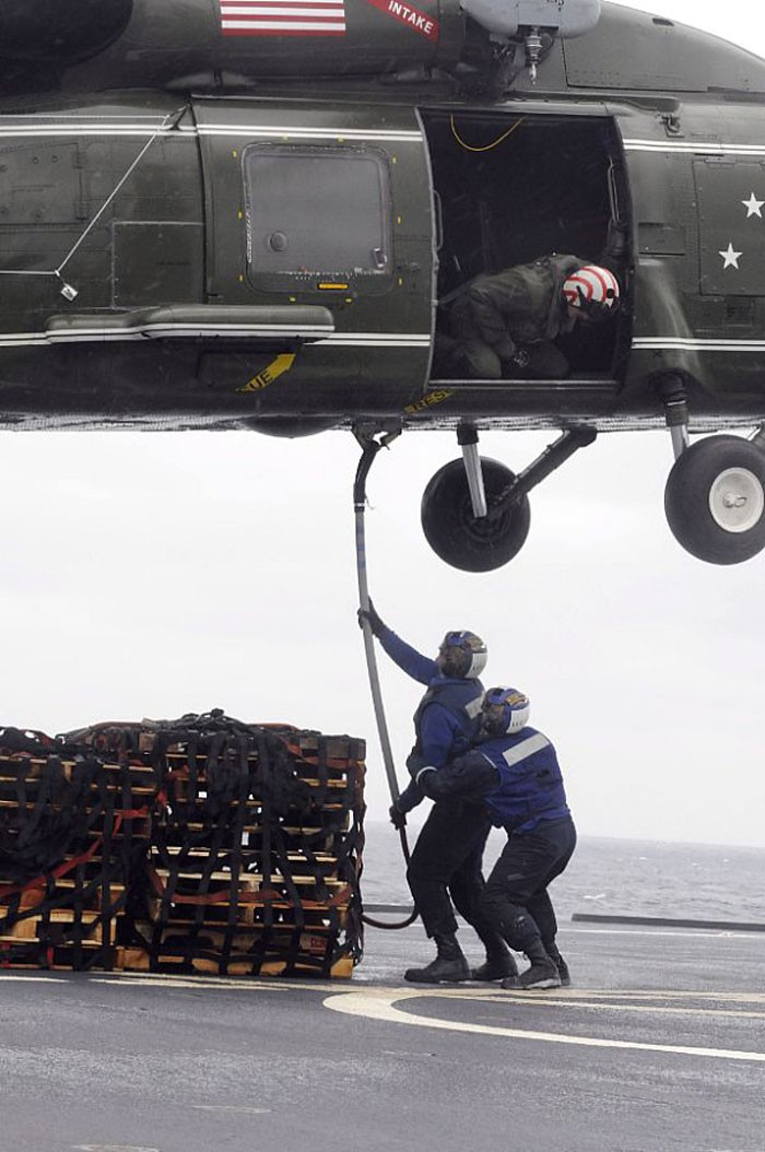 Hai thuỷ thủ Kameron Maison và Edward Kirtley đang móc hàng hóa để đưa lên một máy bay trực thăng SH-60F Sea Hawk trên tàu USS Blue Ridge tại vùng biển Nhật Bản.